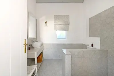 a white bathroom with a sink and a mirror at The Little Vineyard Cottage in Franschhoek