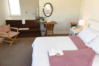 a bedroom with a bed and a sink and a mirror at 138 Marine Beachfront Guesthouse in Hermanus