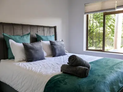 a bedroom with a large bed with towels on it at Sandbaai Breeze in Hermanus