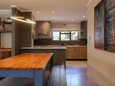a kitchen with a wooden table in the middle at Sandbaai Breeze in Hermanus