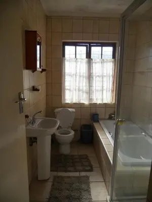 a bathroom with a toilet and a tub and a sink at Twin Oaks Lodges in Cape Town