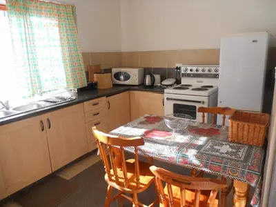 a kitchen with a table with chairs and a refrigerator at Twin Oaks Lodges in Cape Town