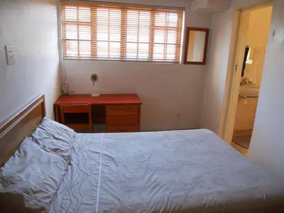 a bedroom with a bed and a desk and a window at Twin Oaks Lodges in Cape Town