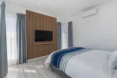 a bedroom with a bed and a flat screen tv at Sunset Sundowners Villa in Cape Town