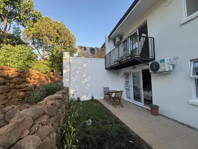a white house with a stone wall and a balcony at Golden Hillside in Somerset West