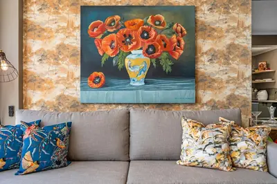 a painting of a vase with orange flowers in it at Waves and Wildflowers in Cape Town