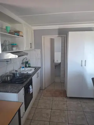 a kitchen with white cabinets and a white refrigerator at White house apartment in Cape Town