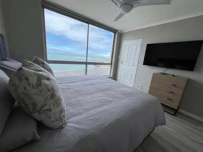 a bedroom with a white bed with a large window at Odeon Ocean View in Strand