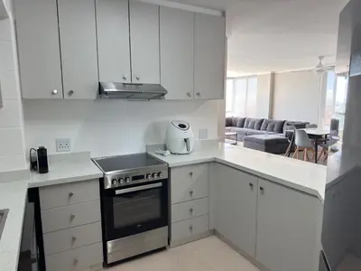 a kitchen with white cabinets and a stove top oven at Odeon Ocean View in Strand