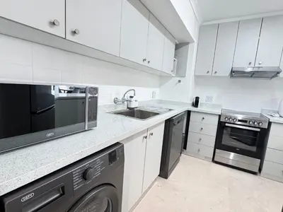a white kitchen with a sink and a stove at Odeon Ocean View in Strand