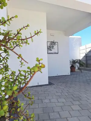 a white building with a sign on the wall at Green Olive Luxury Stay - Cozy, modern and central in Tygerberg Hills