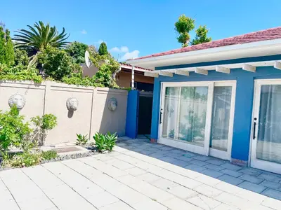 a blue house with a fence and a patio at Blouberg kiters in Cape Town