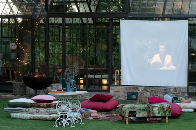 a woman laying on the grass in front of a large screen at Le Grand Jardin Villa in Kayamnandi