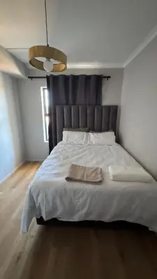 a bedroom with a large white bed with a silver headboard at Cape on Popham apartment in Cape Town