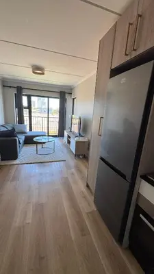 a living room with a couch and a refrigerator at Cape on Popham apartment in Cape Town