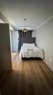 a bedroom with a white bed and a wooden floor at Cape on Popham apartment in Cape Town