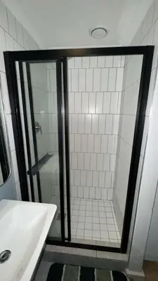 a shower with a glass door next to a sink at Cape on Popham apartment in Cape Town