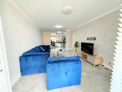 a living room with blue couches and a fireplace at Italian luxe 6 sleeper apartment near canal walk in Cape Town