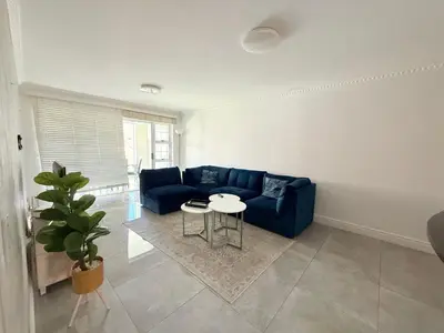 a living room with a blue couch and a table at Italian luxe 6 sleeper apartment near canal walk in Cape Town