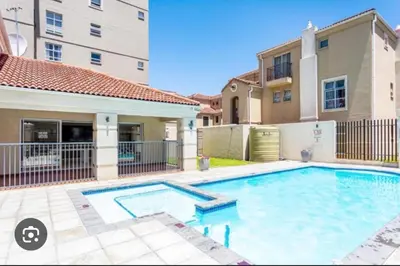 a swimming pool in front of a house at Italian luxe 6 sleeper apartment near canal walk in Cape Town