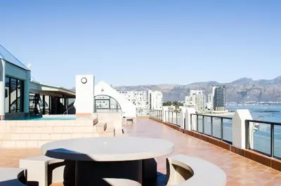 a balcony with a table and a view of the water at The Strand Pavillion in Strand