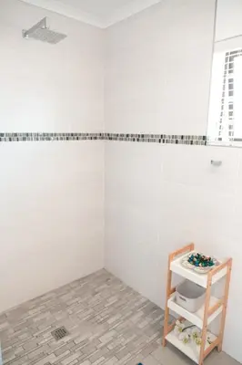 a bathroom with white tiled walls and a walk in shower at Abalone at Hermanus Reefs in Hermanus