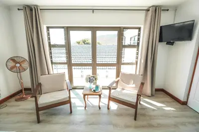 a living room with two chairs and a table and a tv at Abalone at Hermanus Reefs in Hermanus