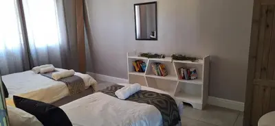 a room with two beds and a shelf with books at Family Cottage no 4 in Wellington