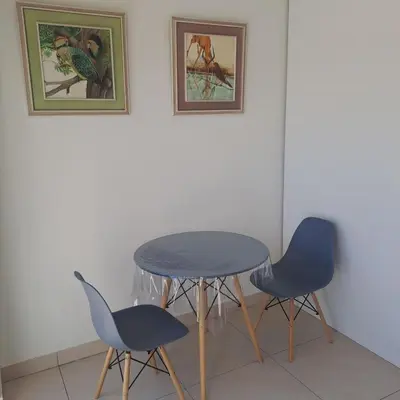 a table and two chairs in a room with paintings at Peaceful one bedroom guesthouse in Rondebosch in Cape Town