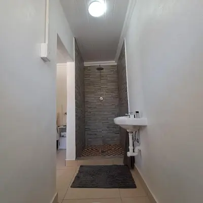 a white bathroom with a sink and a shower at Peaceful one bedroom guesthouse in Rondebosch in Cape Town