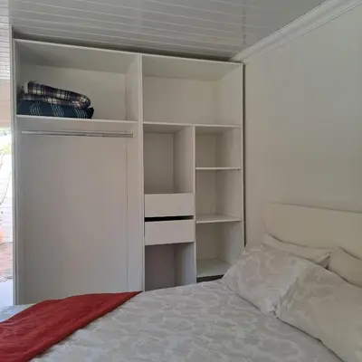 a white bedroom with a bed and white shelves at Peaceful one bedroom guesthouse in Rondebosch in Cape Town