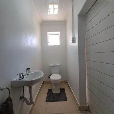a white bathroom with a toilet and a sink at Peaceful one bedroom guesthouse in Rondebosch in Cape Town