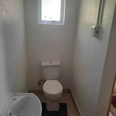 a bathroom with a toilet and a sink and a window at Peaceful one bedroom guesthouse in Rondebosch in Cape Town
