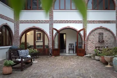 a building with arches and a bench in a courtyard at Mountain and Tides in Kleinmond