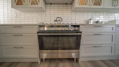 a kitchen with a stainless steel stove and white cabinets at Swallows Rest - Benguela Cove in Hermanus