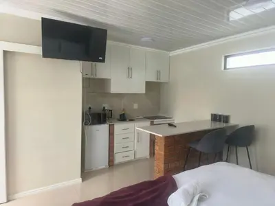a kitchen with white cabinets and a counter top at On 10 breezand road in Cape Town