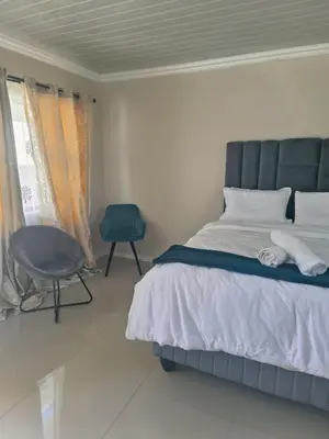 a bedroom with a bed and a chair and a window at On 10 breezand road in Cape Town