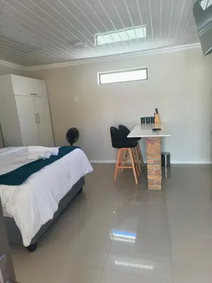 a bedroom with a bed and a desk in it at On 10 breezand road in Cape Town