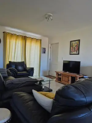 a living room with couches and a flat screen tv at Apartment in Milnerton, Royal Ascot, Cape Town in Cape Town