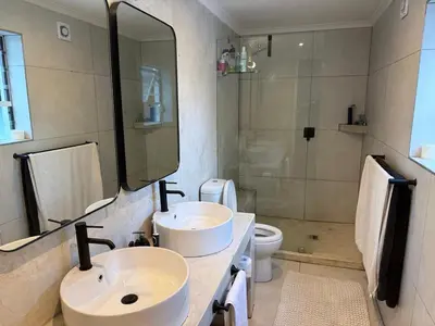 a bathroom with two sinks and a shower and a toilet at Modern & Secure 3-Bed Home with Pool & Garden in Cape Town