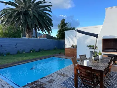 a backyard with a swimming pool and a table and chairs at Modern & Secure 3-Bed Home with Pool & Garden in Cape Town