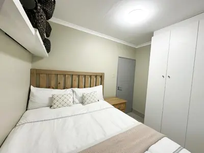 a bedroom with a bed with white sheets and pillows at 29 on Windsor Rooms- in Camelot,Kuilsriver in Silver Sands