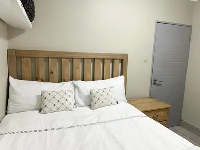 a bedroom with a bed with white sheets and pillows at 29 on Windsor Rooms- in Camelot,Kuilsriver in Silver Sands