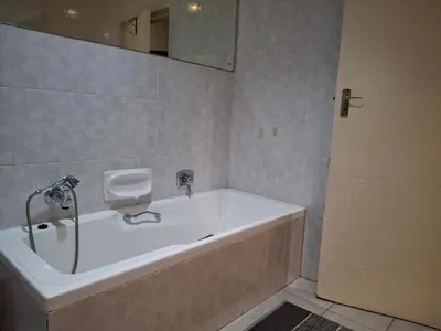 a bathroom with a tub and a mirror and a door at Spacious Suite in Somerset West in Somerset West