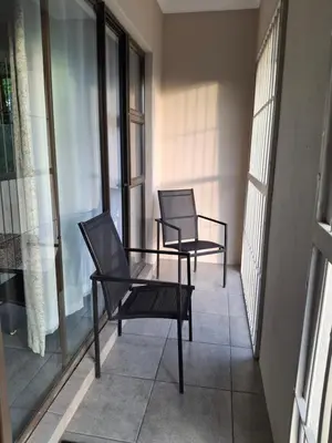 two chairs sitting on a balcony with windows at Spacious Suite in Somerset West in Somerset West