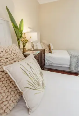 a bedroom with two beds and a table with a pillow at Charming Historic Home in Central Stellenbosch in Stellenbosch