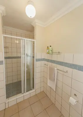a bathroom with a glass shower and white tiles at Charming Historic Home in Central Stellenbosch in Stellenbosch