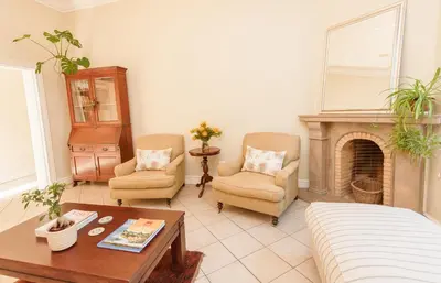 a living room with two chairs and a fireplace at Charming Historic Home in Central Stellenbosch in Stellenbosch