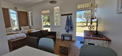 a living room with a couch and a bed at The Barracks at Brigadoon Village in Bettyʼs Bay