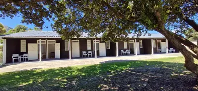 a building with chairs and a tree in the foreground at The Barracks at Brigadoon Village in Bettyʼs Bay
